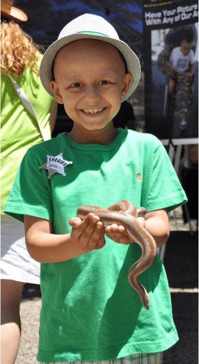 Pediatric cancer patient smiling holding a snake