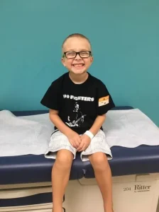 A small american kid if recovering from cancer tratement is smiling happily